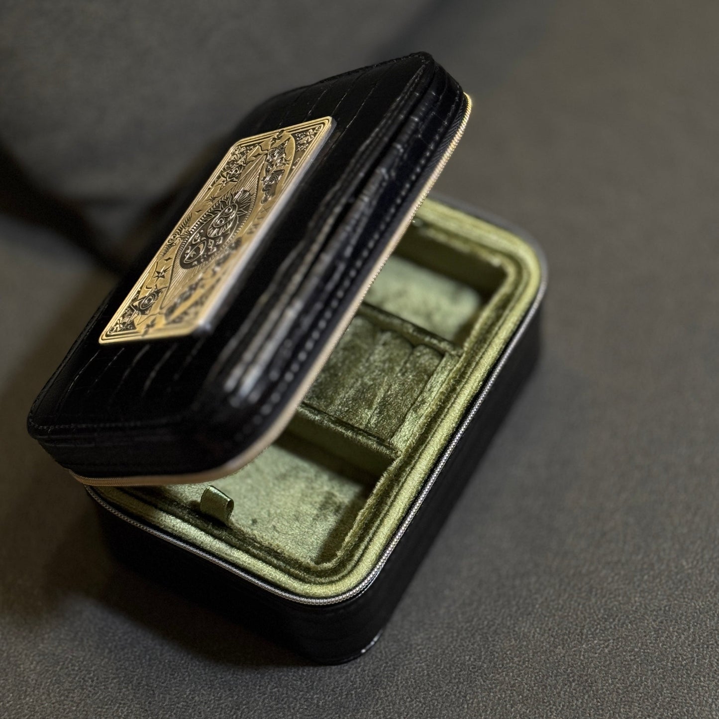 Small black jewelry box with a gold emblem on a gray background